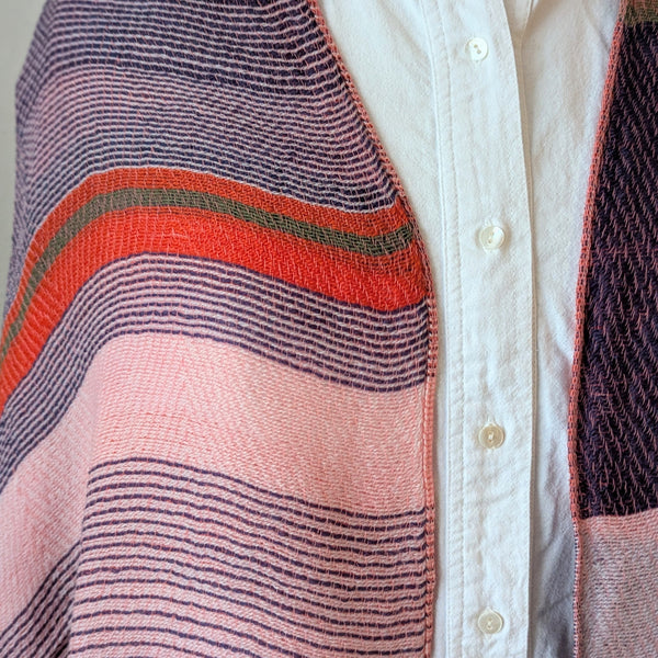 Close-up of a woven scarf with colorful stripes on a white shirt background