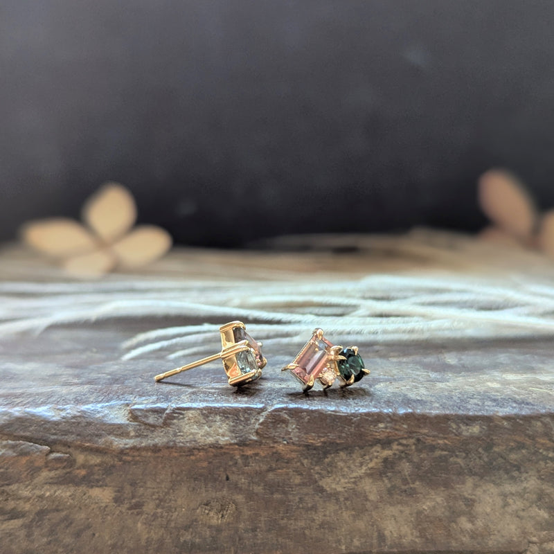 Pair of gold stud earrings with gemstones on a textured surface