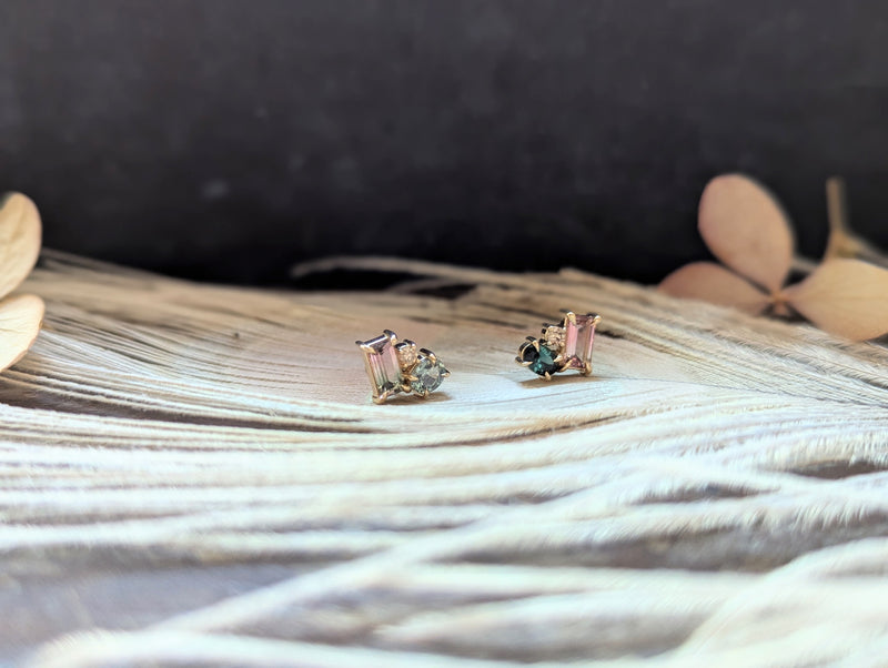 Pair of gold earrings with gemstones on a textured surface