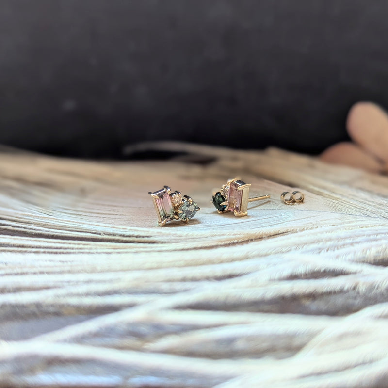 Pair of gold earrings with gemstones on a textured surface