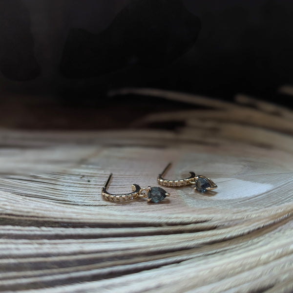 Gold earrings with sapphire gemstones and dimonds on a wooden surface