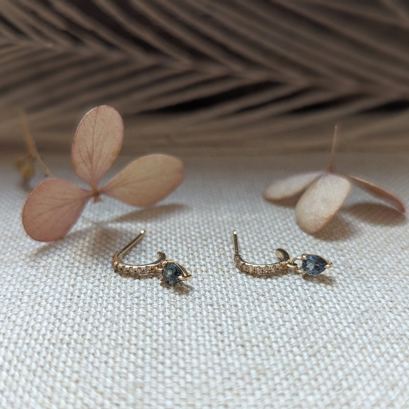 Gold earrings with sapphire gemstones and dimonds on a wooden surface