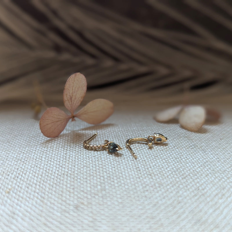 Gold earrings with sapphire gemstones and dimonds on a wooden surface