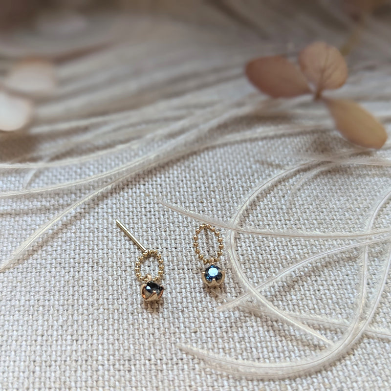 Pair of gold earrings with gemstones on a textured fabric background