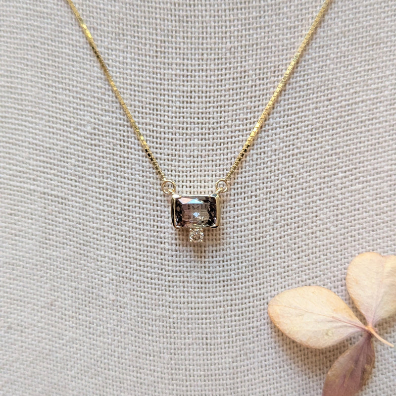 Gold necklace with a Watermelon Tourmaline gemstone and diamond pendant on a light gray background