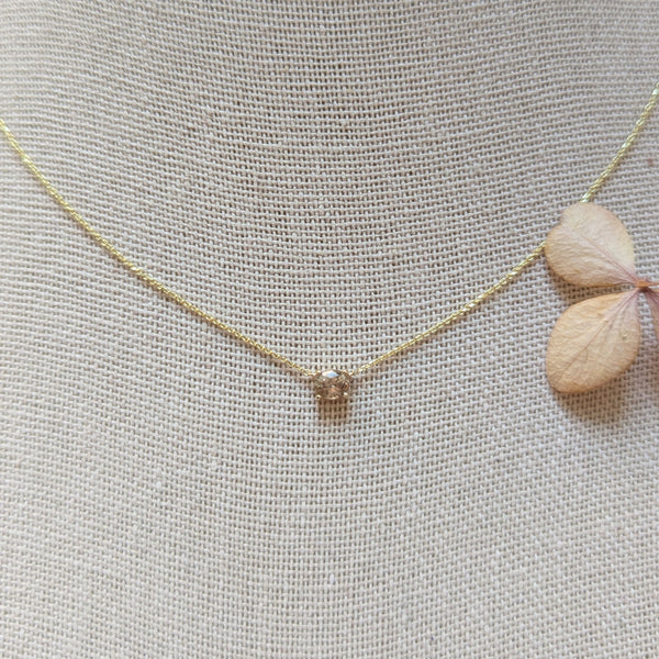 Gold necklace with a small pendant on a textured gray background