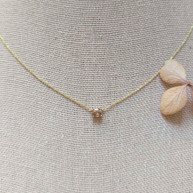 Gold necklace with a small pendant on a textured gray background