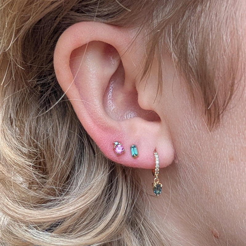 Close-up of an ear with multiple earrings against a blurred background