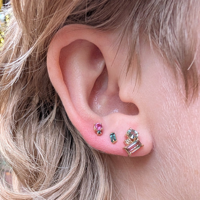 Close-up of an ear with multiple gemstone earrings.