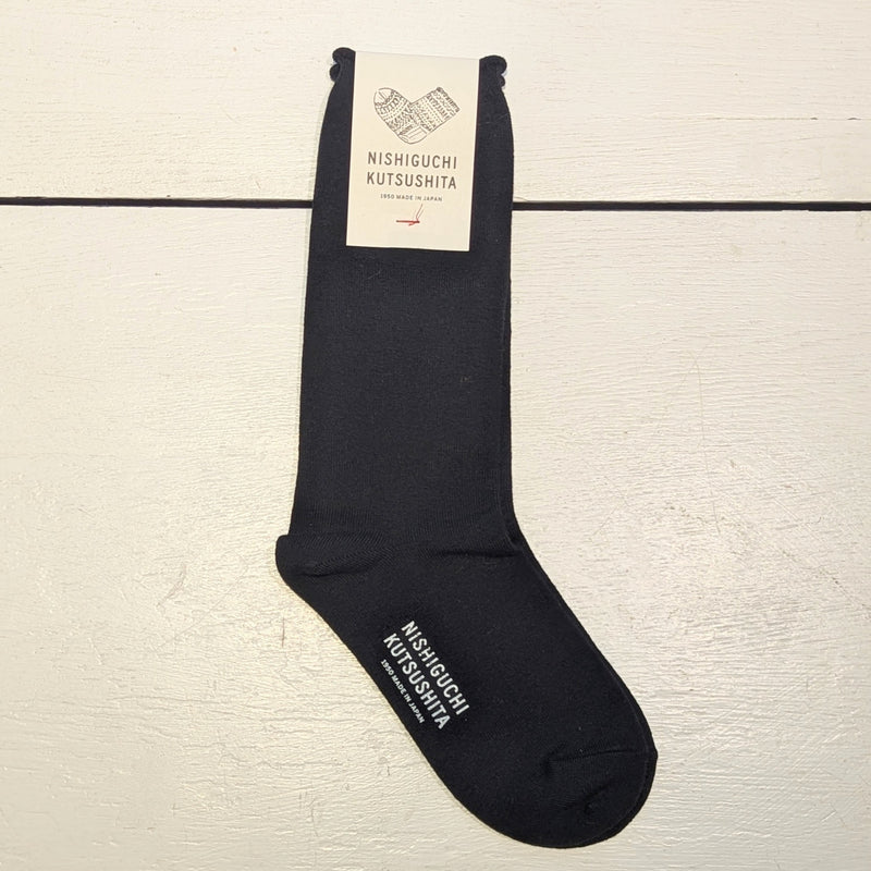 Pair of black socks with logo "Nishiguchi Kutsushita" on the bottom of the foot.