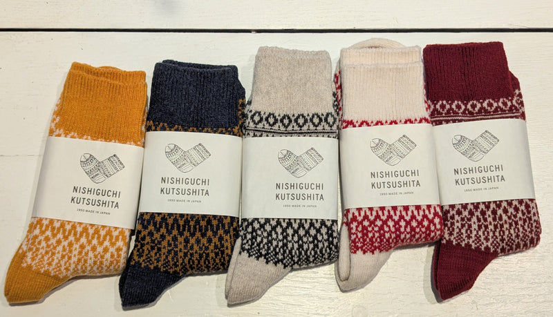 Five pairs of patterned socks with visible branding on a light wooden surface.