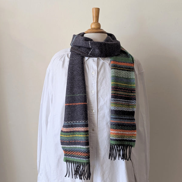 Mannequin wearing a white shirt with a colorful striped scarf draped over it against a plain background