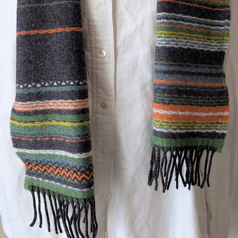 Striped scarf with fringes draped over a white shirt