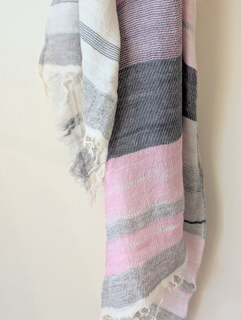 Striped scarf with pink, gray, and white pattern on a plain background