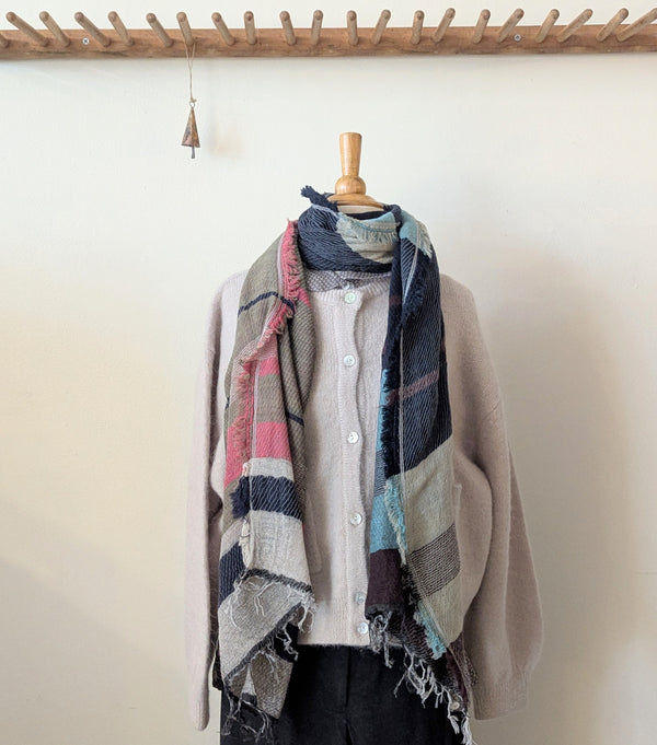 Plaid scarf draped over a mannequin against a white wall