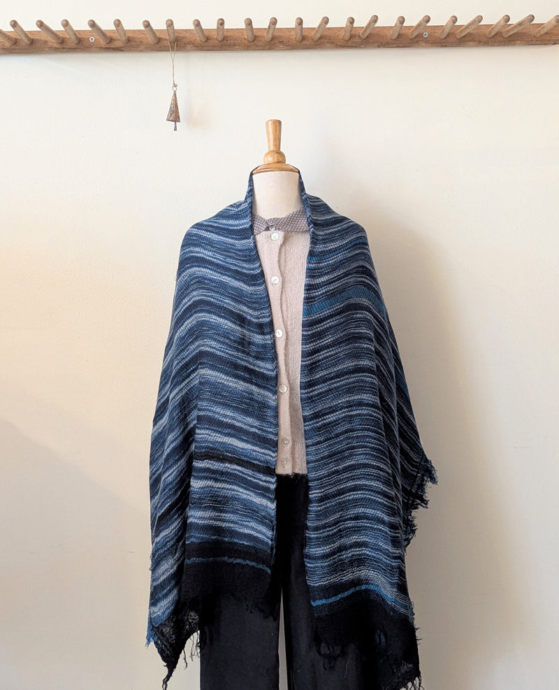 Mannequin wearing a blue striped shawl against a white wall