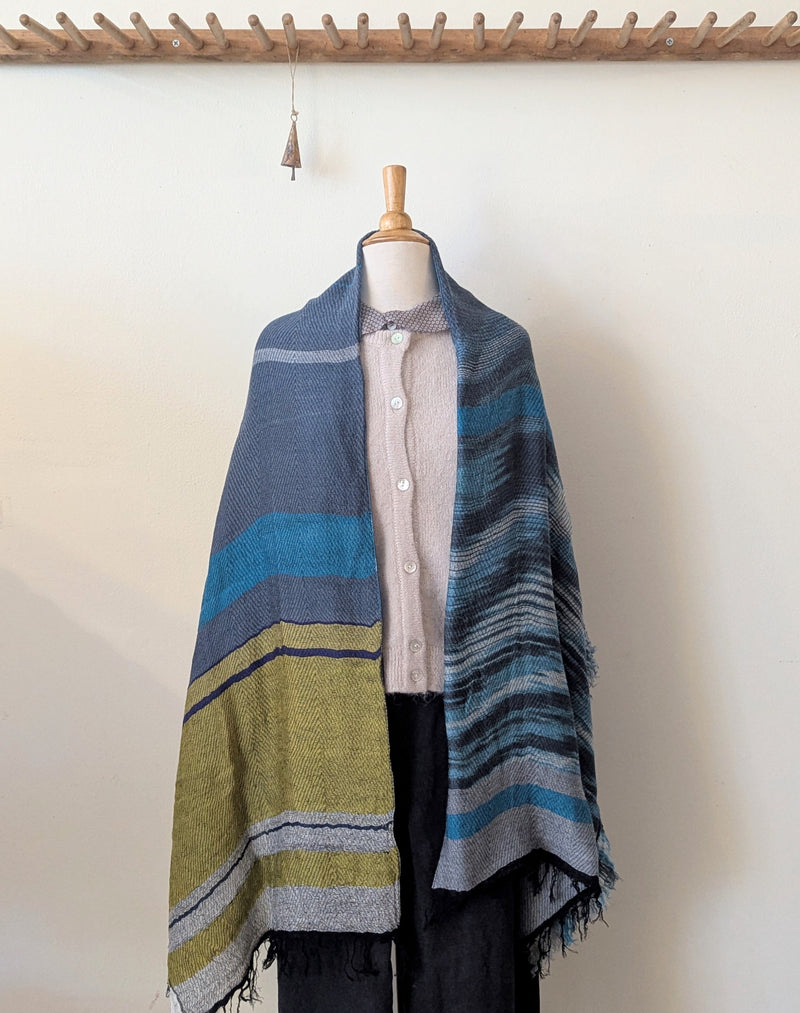 Mannequin wearing a striped poncho with a plain background