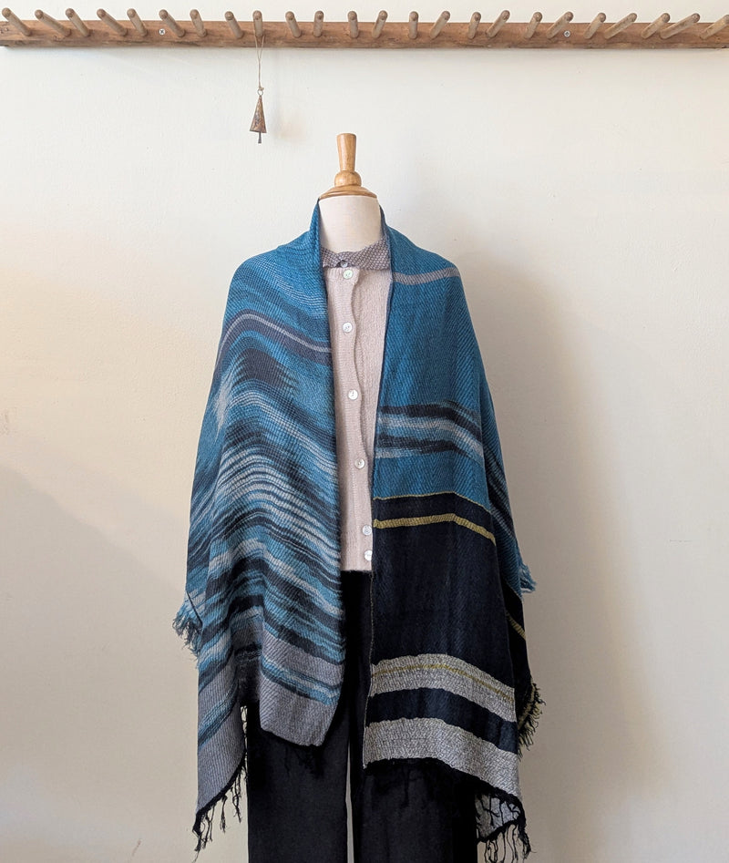 Mannequin wearing a blue striped shawl against a white wall