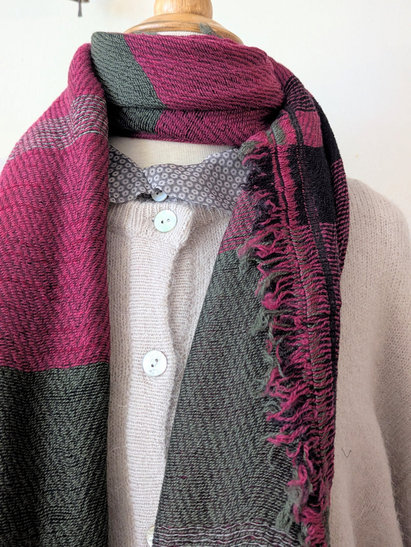 Mannequin wearing a pink and gray patterned scarf with a plain background