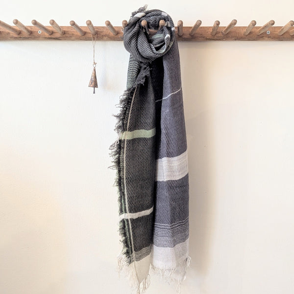 Black and white striped scarf hanging on a wooden rack against a white wall.