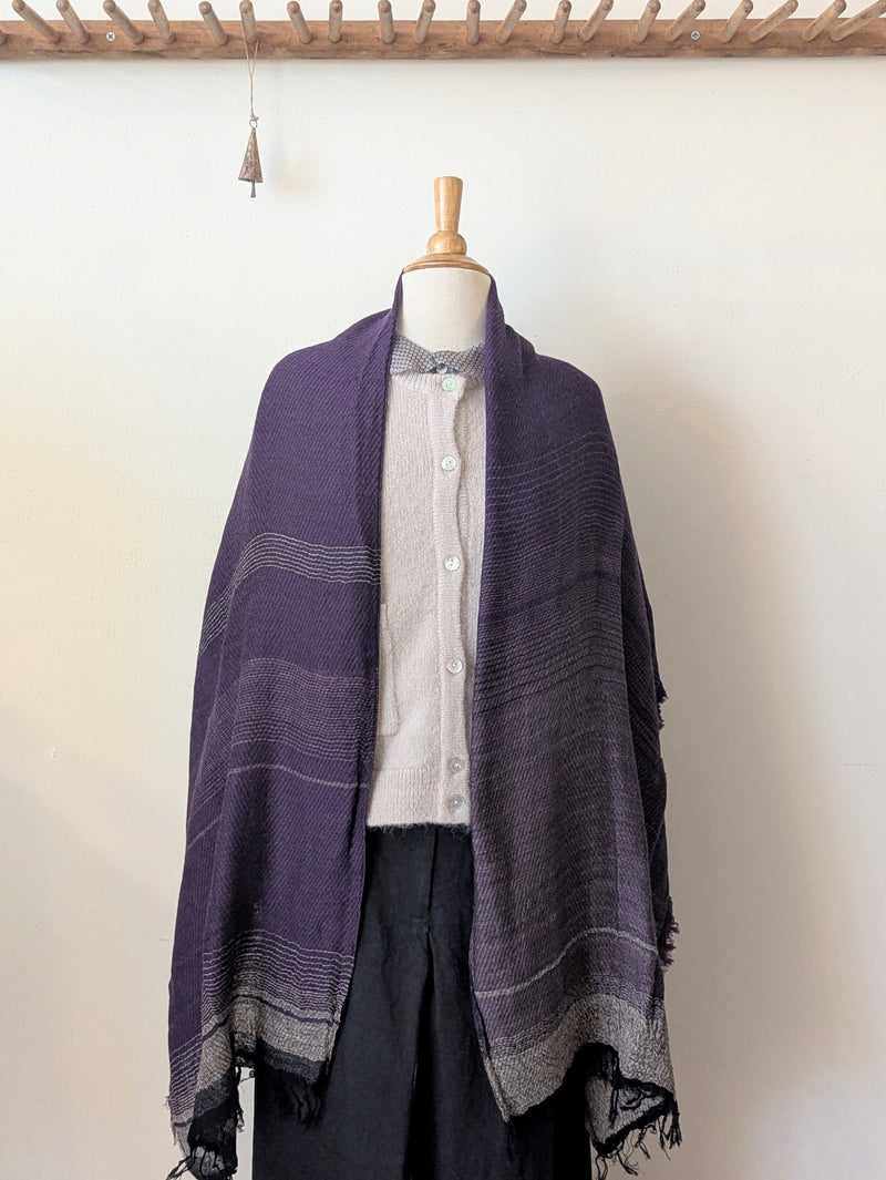 Mannequin wearing a purple scarf with a white shirt and dark pants against a plain background