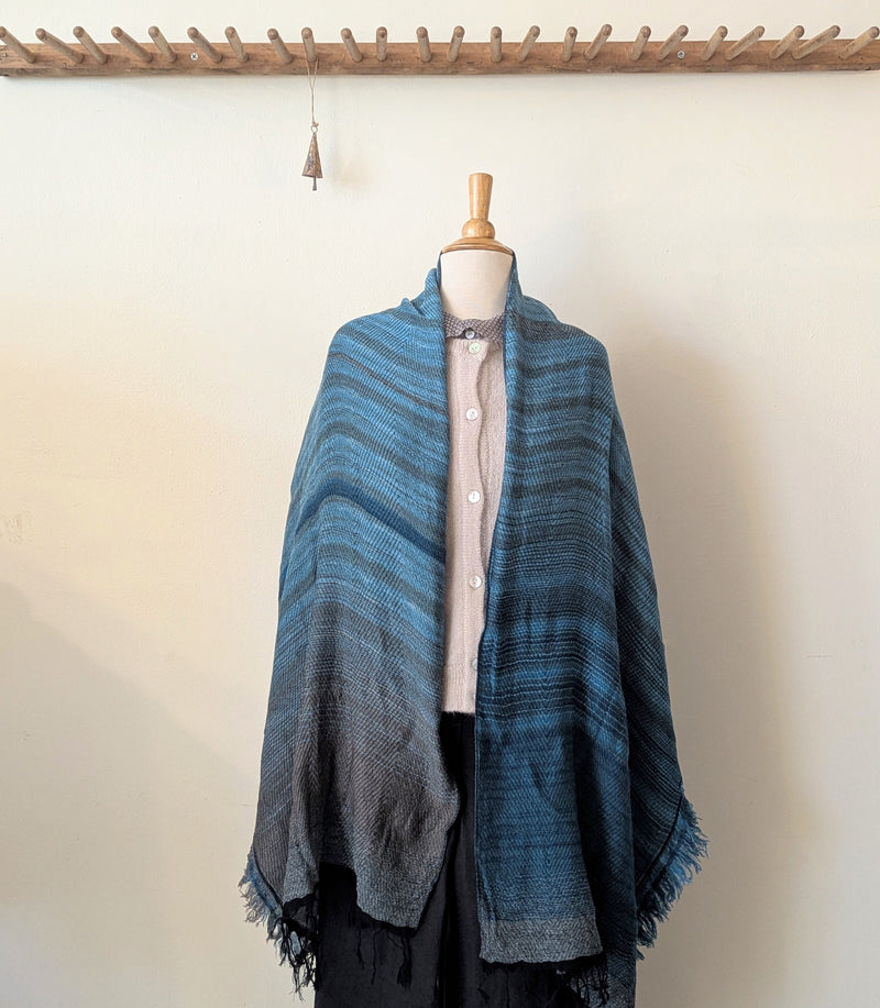 Blue striped shawl draped over a mannequin against a white wall.