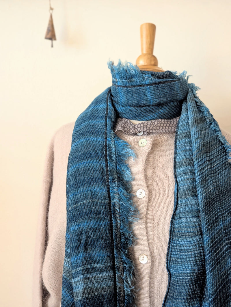 Blue stripe scarf draped over a mannequin against a white wall.