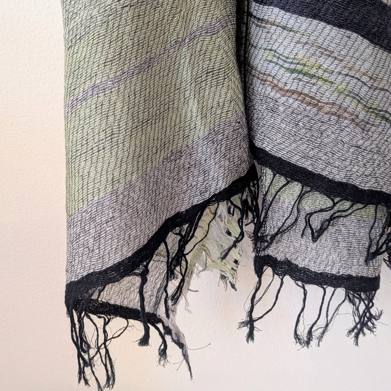Textured scarf with black fringe on a light background