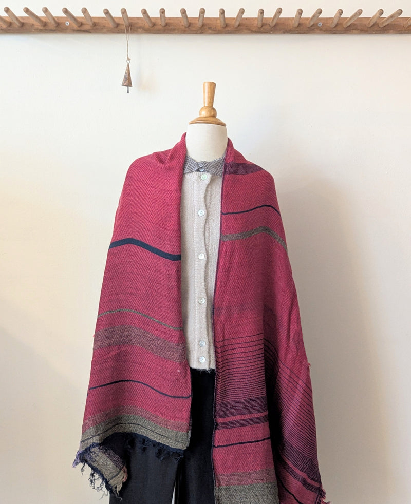 Mannequin wearing a pink striped shawl with a plain background