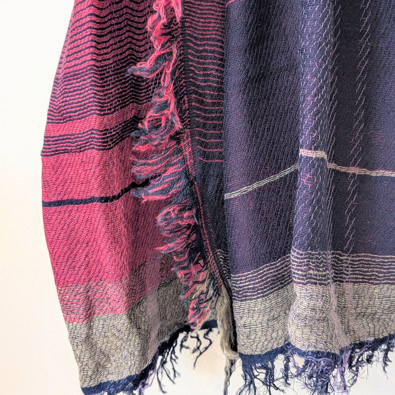 Two plaid scarves with fringe details, one pink and black, the other blue and white, on a light background.