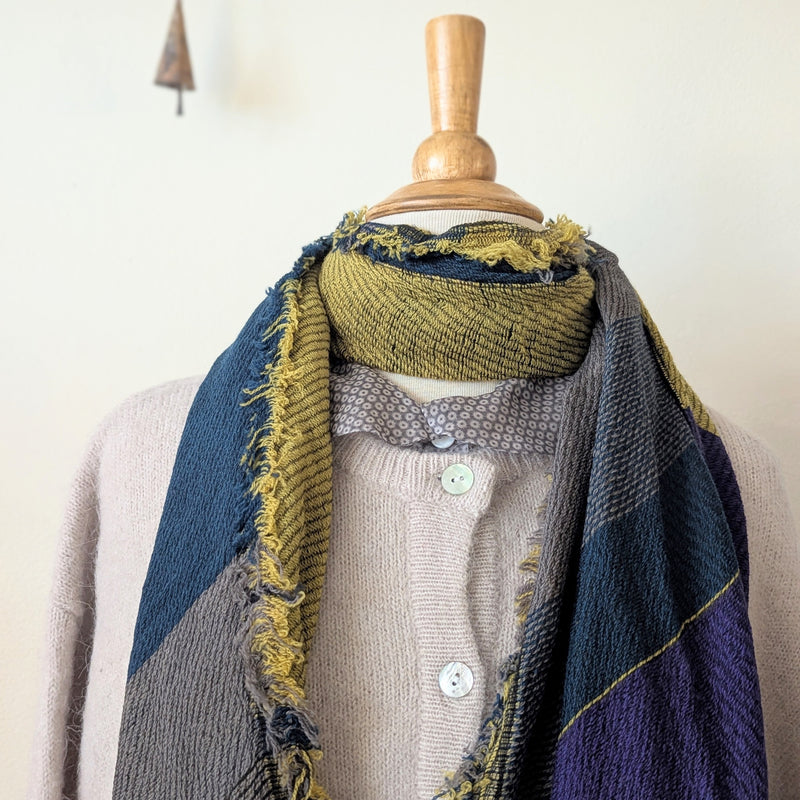 Mannequin wearing a  scarf with a textured pattern on a plain background