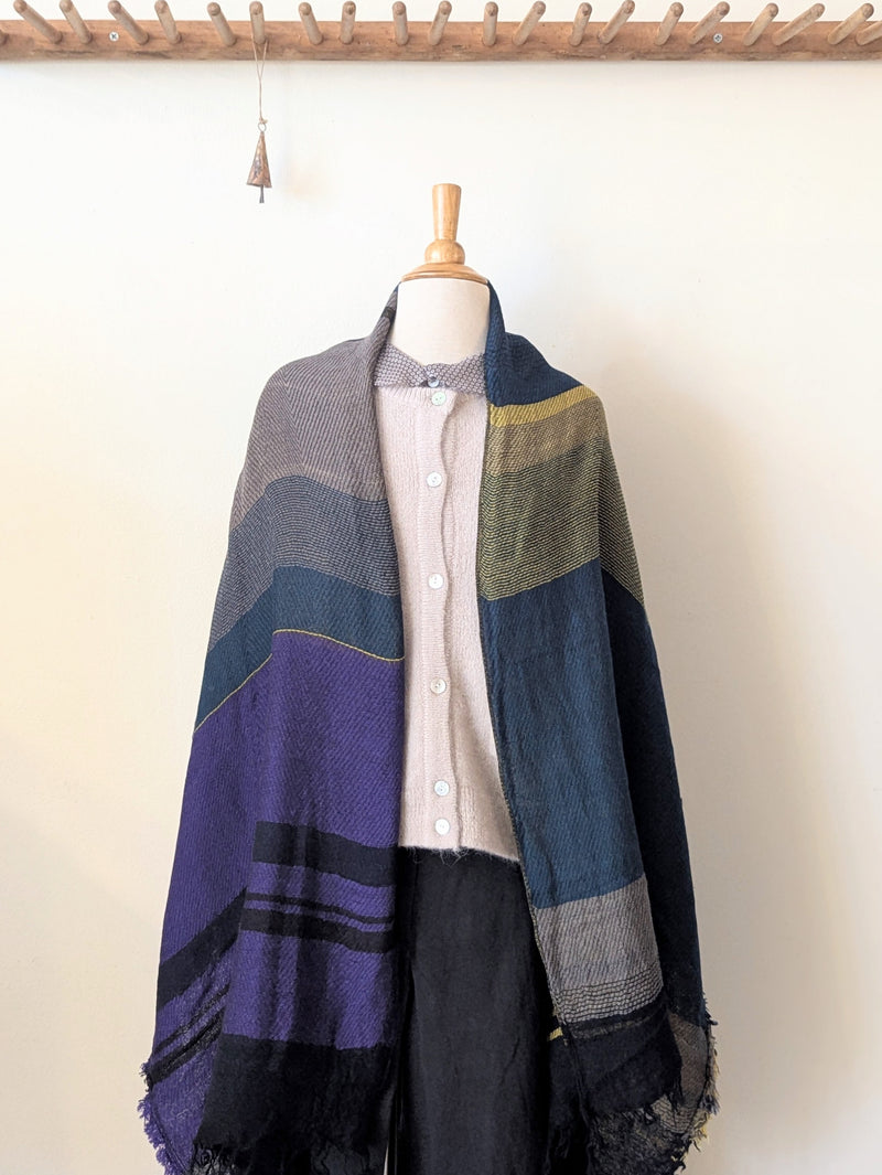 Mannequin wearing a colorful striped shawl against a white background