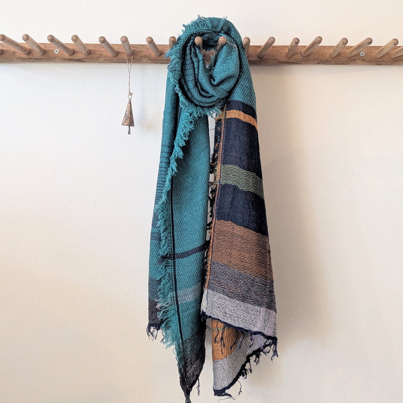 blue, Navy, and orange stripe scarf wrapped around  wooden hanger against white background