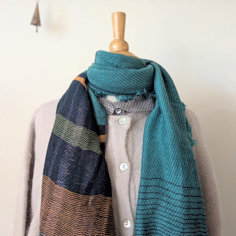 Teal scarf draped over a mannequin with a neutral background