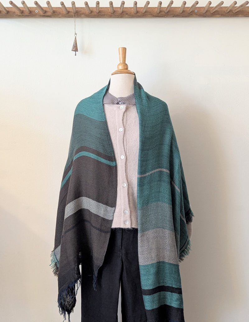 Mannequin wearing a striped shawl over a shirt and pants against a white background