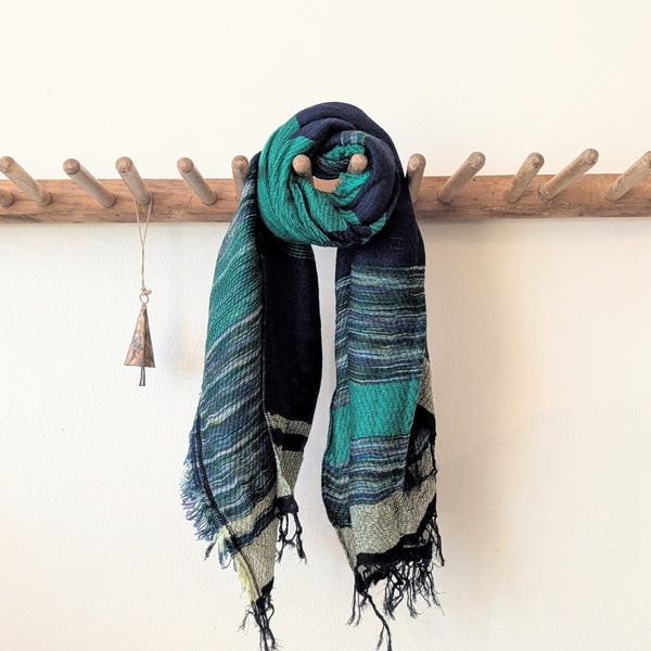 Colorful scarf draped over a wooden rack with a white background