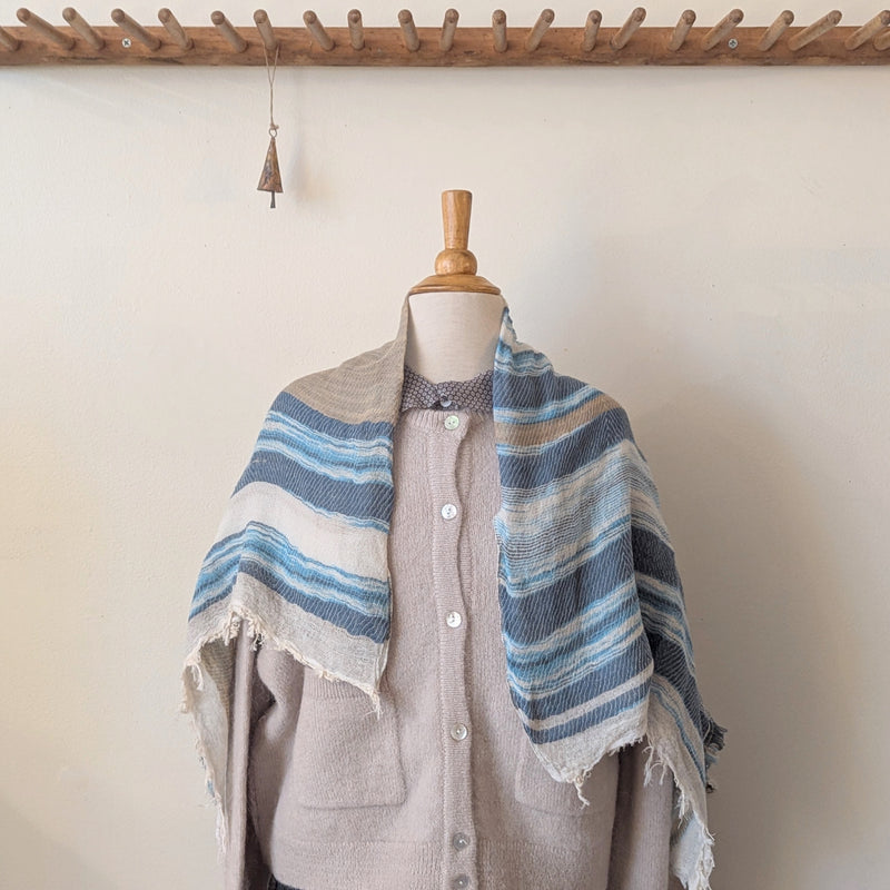 Mannequin wearing a striped shawl with a wooden hook in the background