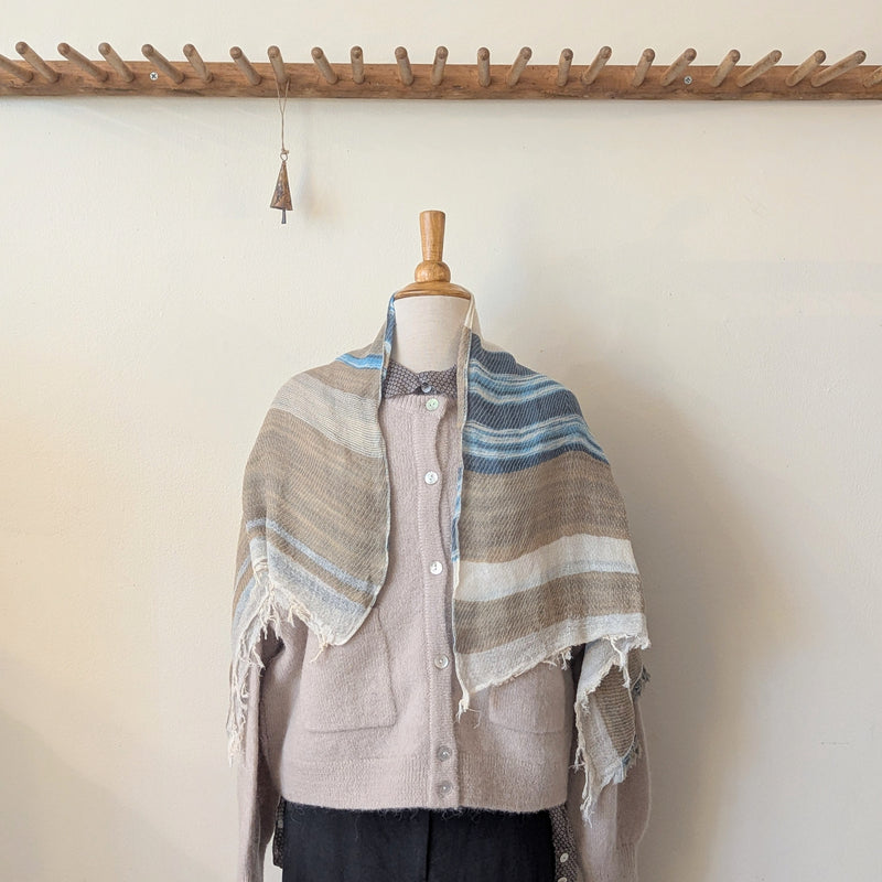 Mannequin wearing a striped shawl with a wooden rack in the background