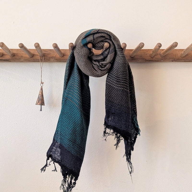 Scarf hanging on a wooden rack against a white wall
