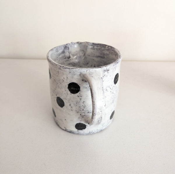 Ceramic pitcher with black speckles on a white background