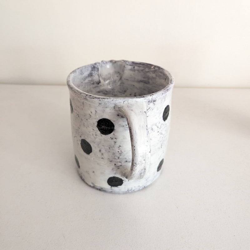 Ceramic pitcher with black speckles on a white background
