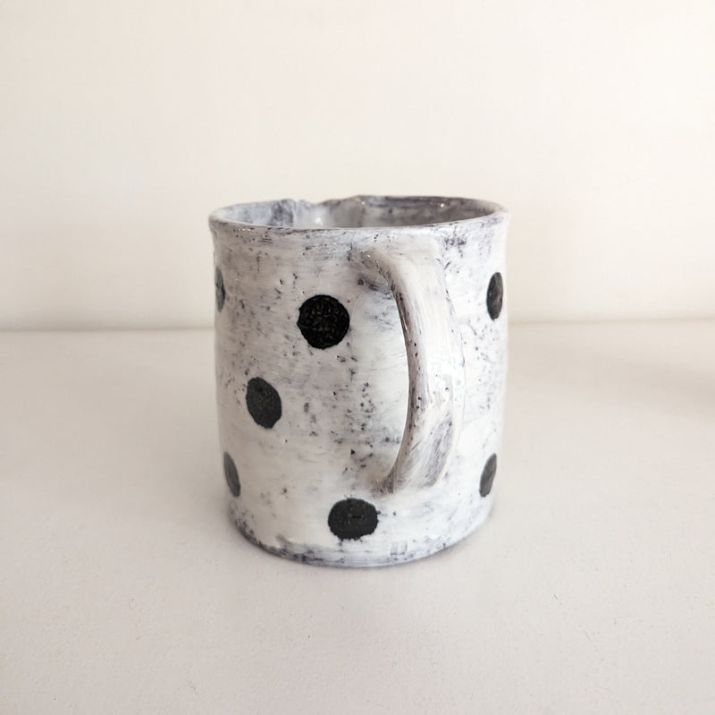 Ceramic mug with black dot patterns on a white background