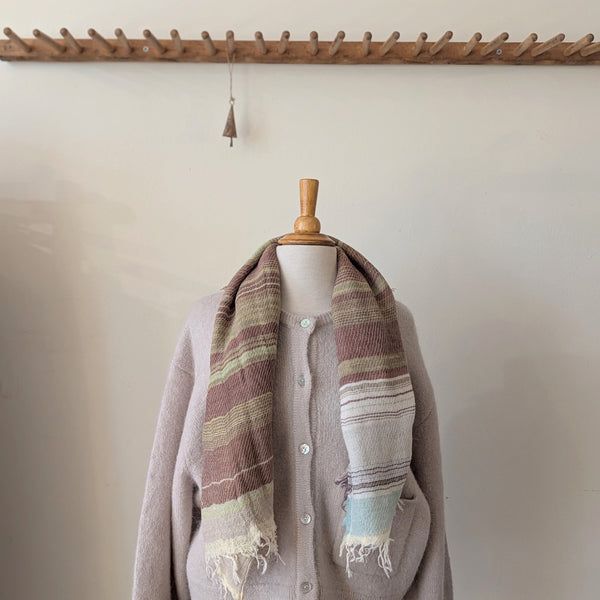 Mannequin wearing a brown cardigan with a striped scarf against a neutral background