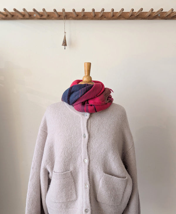 Mannequin wearing a gray cardigan with a red and blue plaid scarf draped over it, against a plain background.