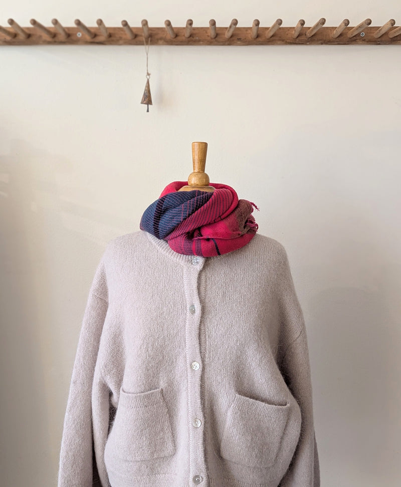 Mannequin wearing a gray cardigan with a red and blue plaid scarf draped over it, against a plain background.