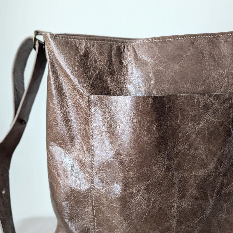 Close-up of a brown leather bag with visible texture on a light background
