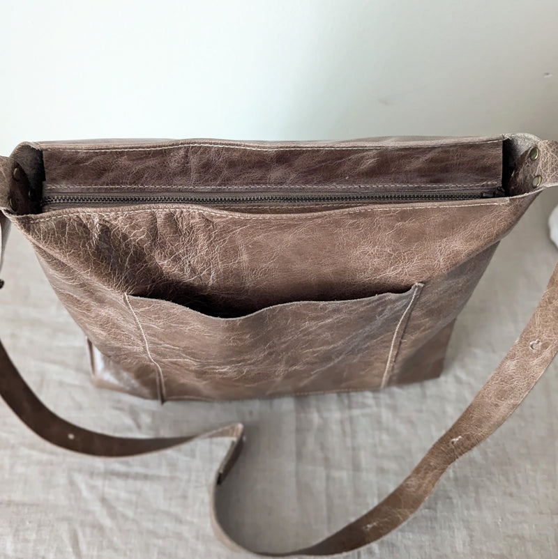 Brown leather bag with a strap on a light background