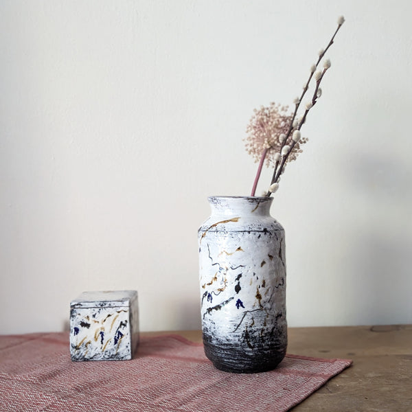 Ceramic vase with decorative elements on a wooden surface with a plain background