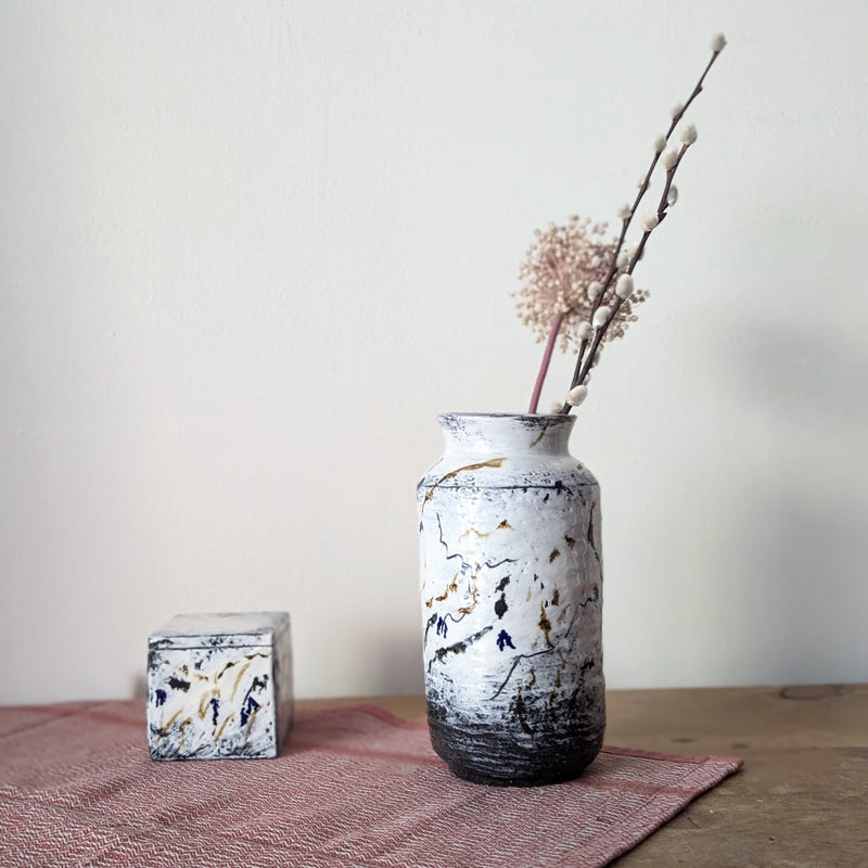 Ceramic vase with decorative elements on a wooden surface with a plain background