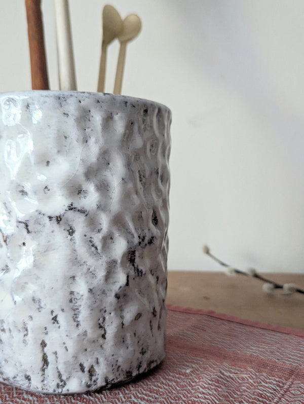Textured ceramic vase with sticks on a neutral background